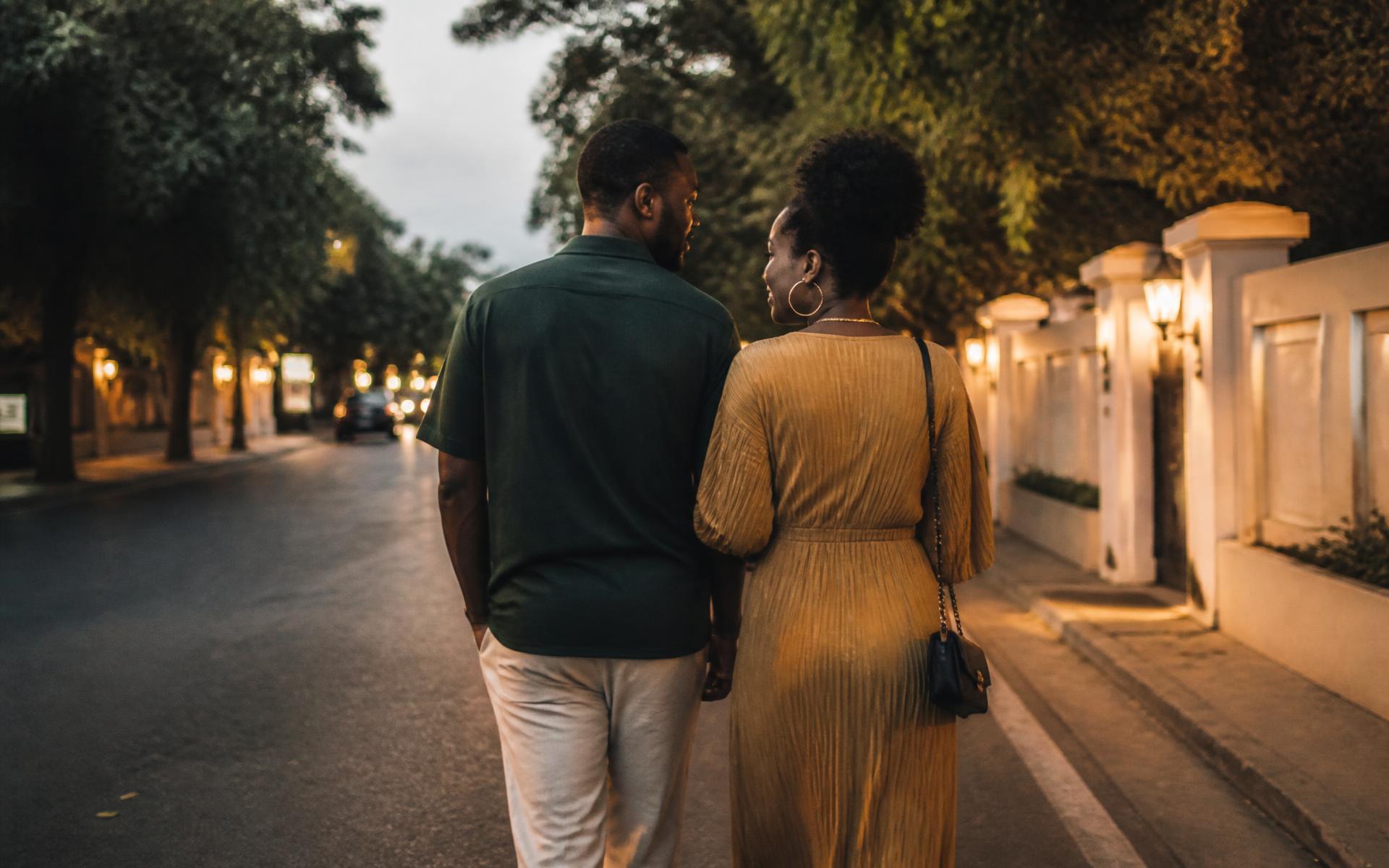 A modern African couple walking together along a quiet tree-lined street in the evening